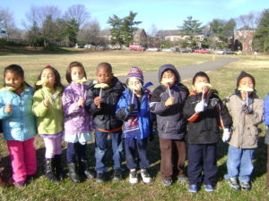 elementary students blowing dandelions