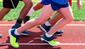 High school boys from the waist down are set up in a groupd to start a running workout with speed.