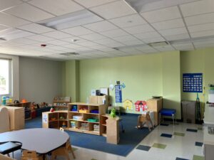 A photo of the Peeps room. There is a table in the foreground, areas of shelves with toys on them, and some posters on the back wall