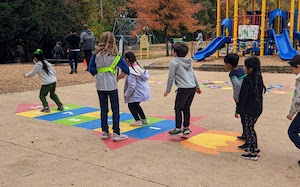 students jumping on painted blacktop surface
